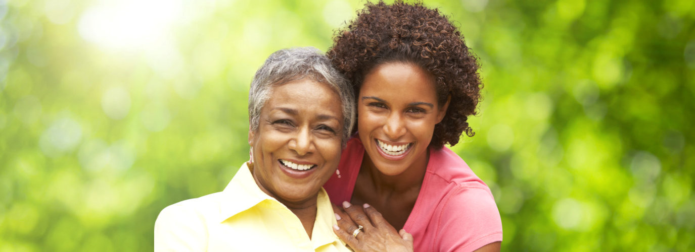 female caregiver hugging senior woman outdoor